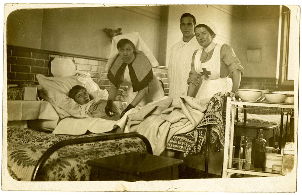 Postcard of nurses tending to a wounded soldier at the First Northern Hospital